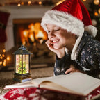 A child wearing a red Santa hat and dark patterned sweater lies on the floor by a warm fireplace, smiling at an open book with a glowing lantern nearby.