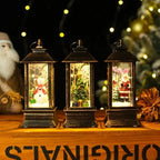 Three decorative lanterns with Christmas scenes inside, on a wooden surface with festive decorations.