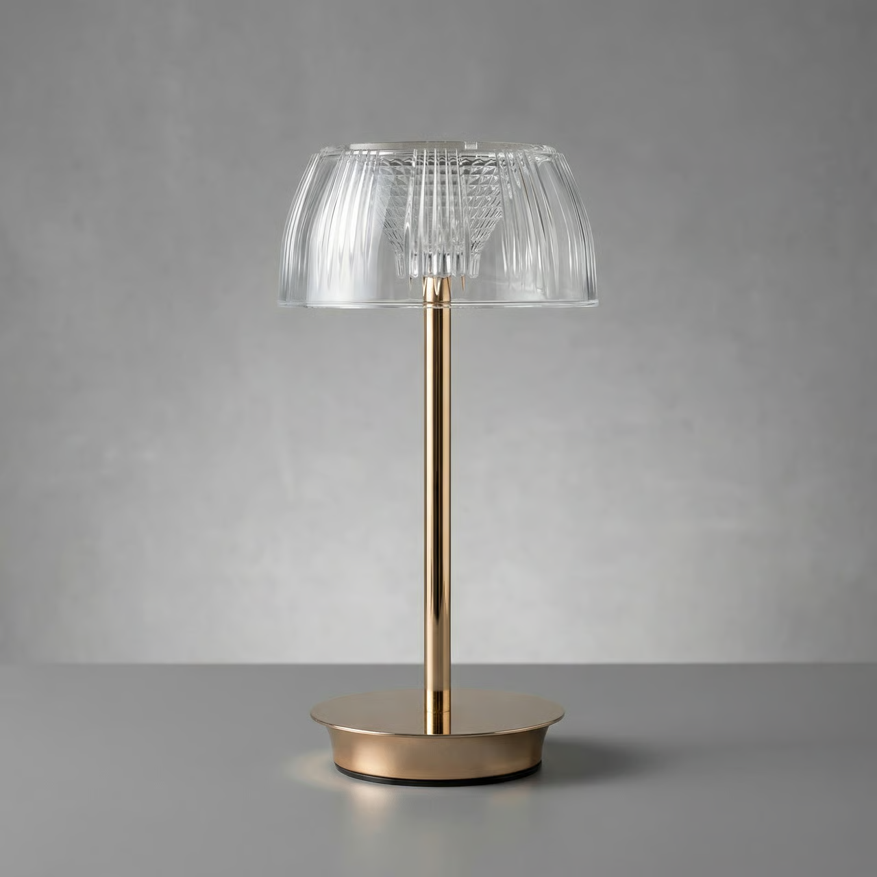 Table lamp with clear glass shade and gold base on a gray background