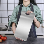 Person holding a metallic cutting board in a kitchen setting