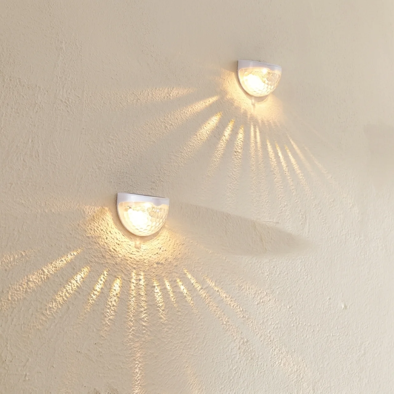 Two wall-mounted lights casting shadows on a textured wall.