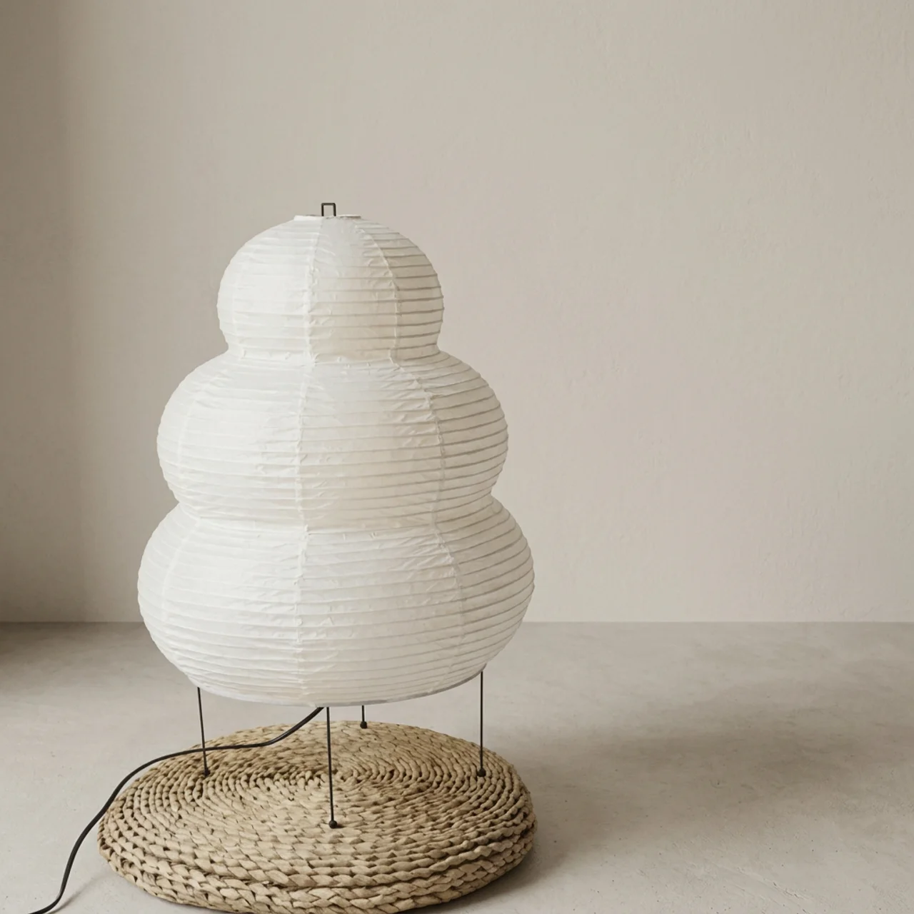 White paper lantern-style lamp with woven base on a neutral background