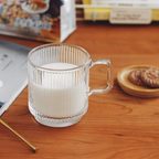 Clear glass mug with milk on a wooden table with cookies and books in the background