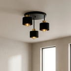 Modern ceiling light fixture with three black lampshades and gold accents on a neutral ceiling.