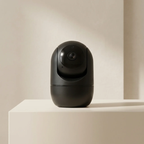 Black security camera on a light beige surface with a neutral background