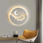 Decorative wall light with moon and cloud design on a wall above a table and chair.