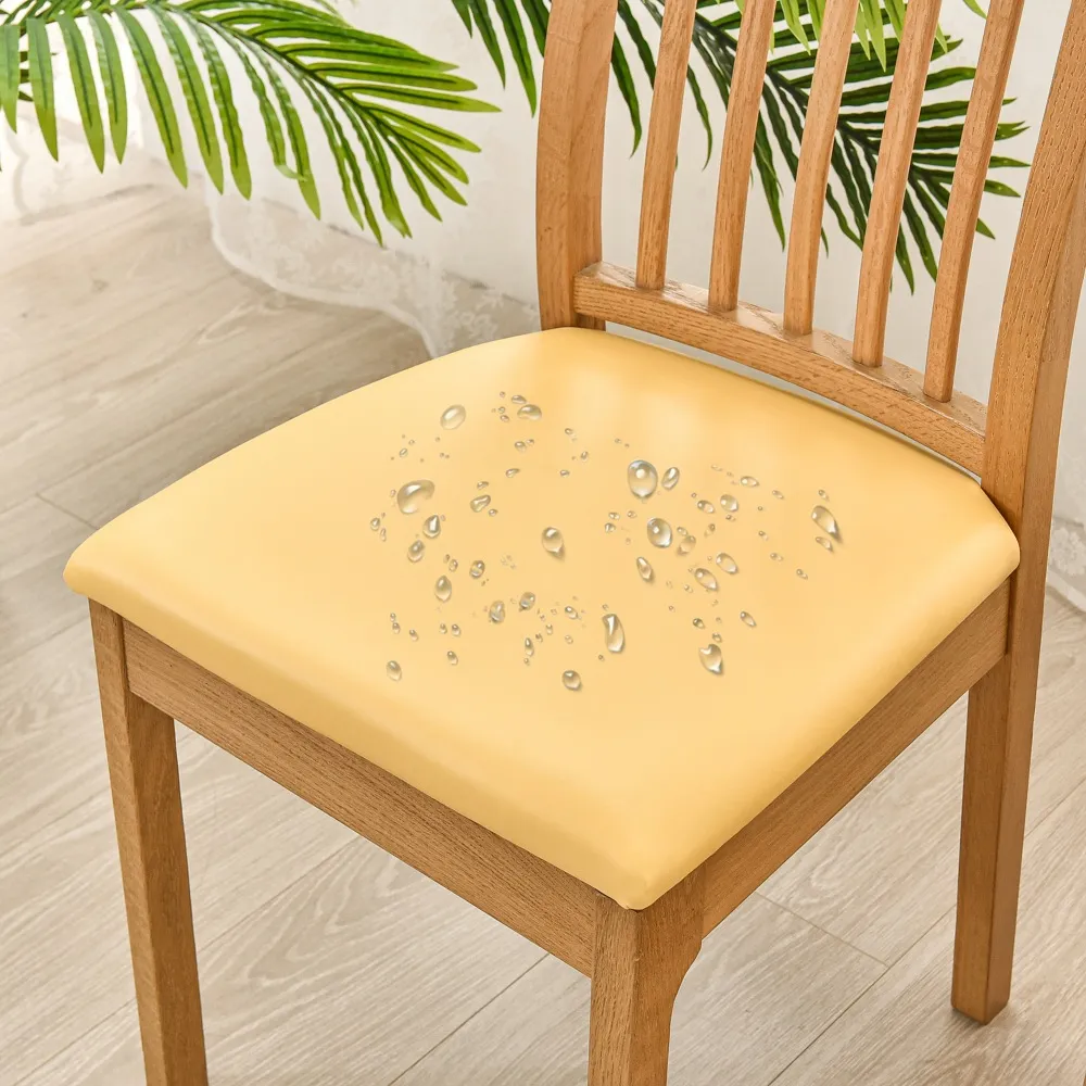 Yellow cushion with decorative elements on a wooden chair, with green leaves in the background.
