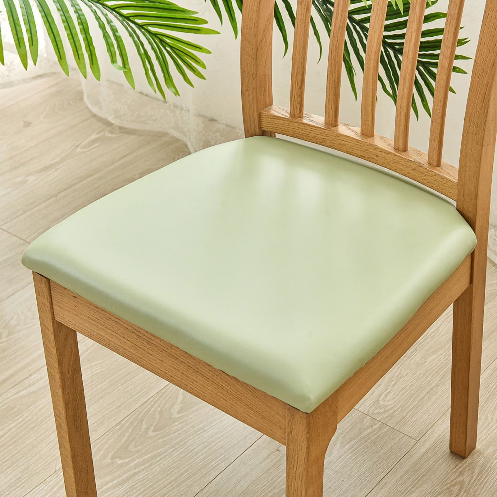 Wooden chair with a green cushion on a light wooden floor.