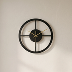 Black wall clock with gold hands on a beige wall