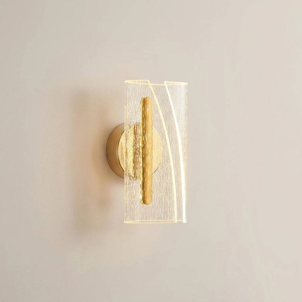 Gold wall sconce with glass shade on a neutral wall