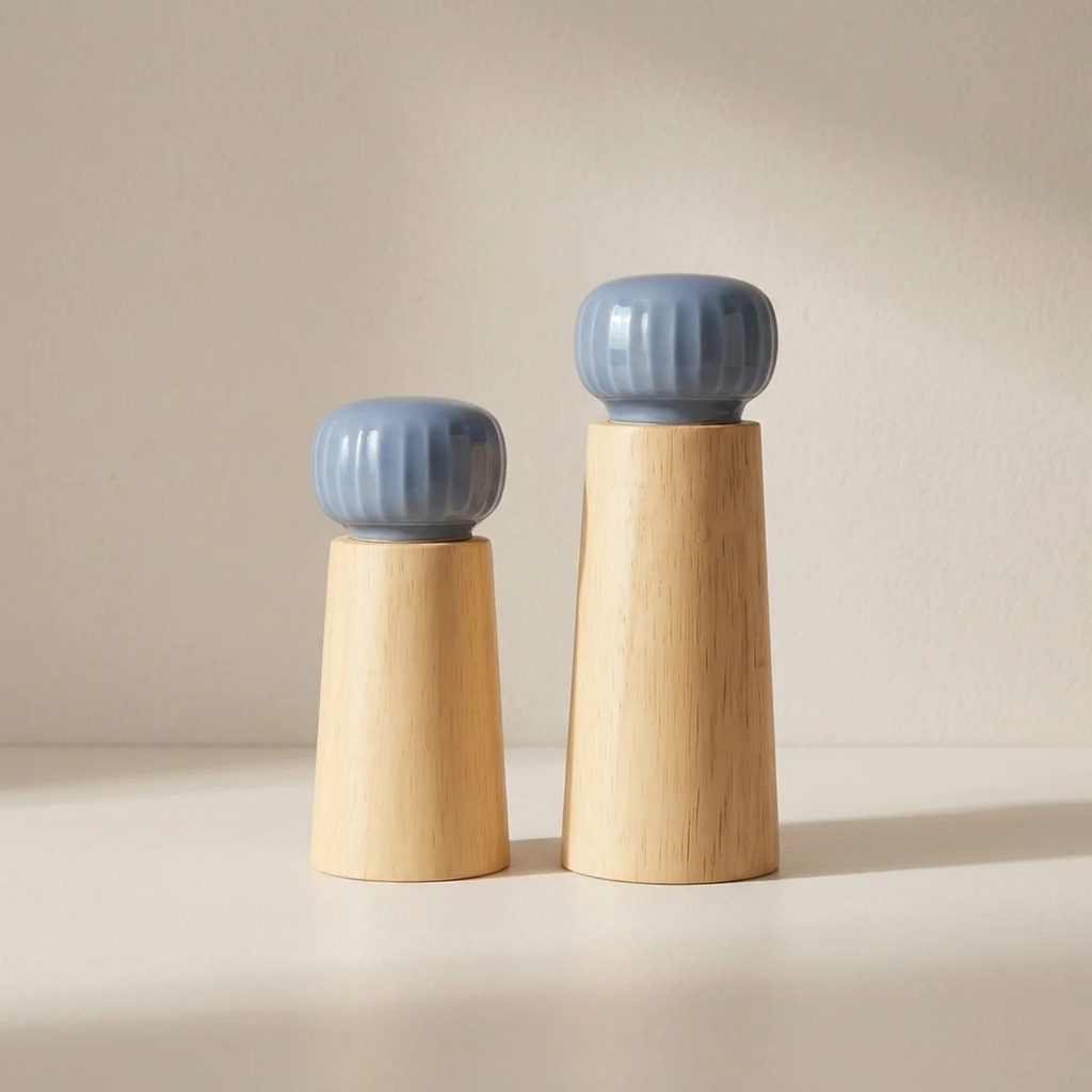 Two ceramic salt and pepper shakers with blue tops and wooden bases on a beige background