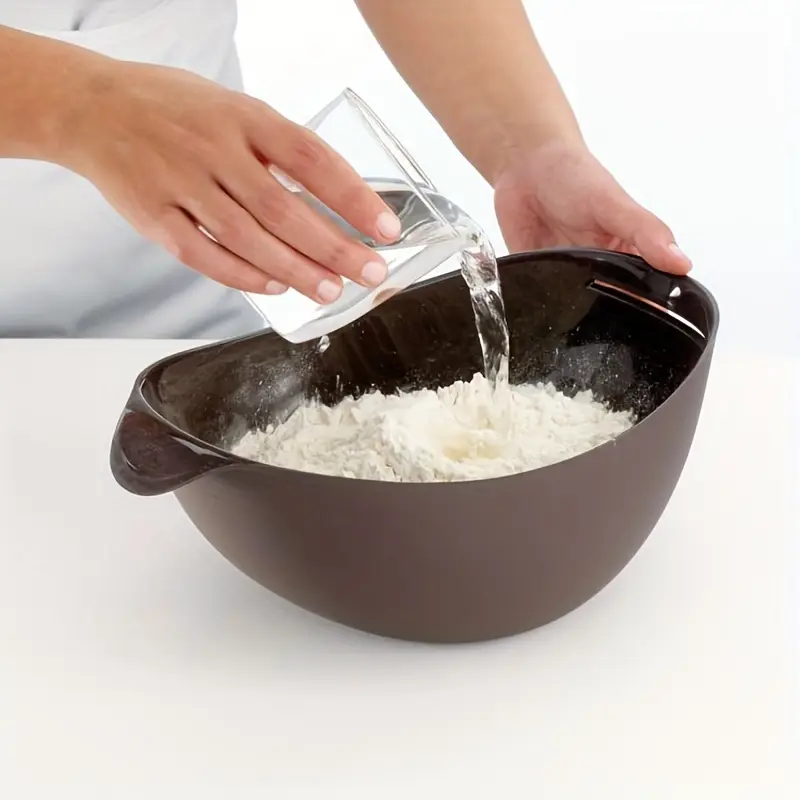 Person pouring water into a bowl of flour on a white background