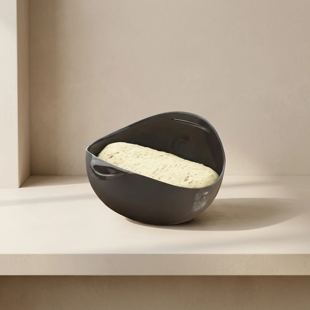Gray ceramic bowl with dough inside on a beige surface