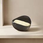 Gray ceramic bowl with dough inside on a beige surface