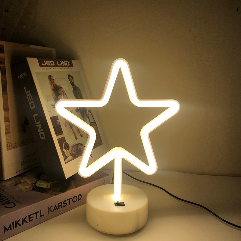 Neon star light on a white surface with books in the background