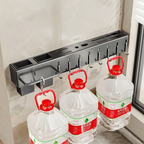 Wall-mounted bottle holder with three large water bottles hanging from it.