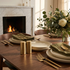 Dining table set with plates, silverware, and a floral arrangement in front of a fireplace.