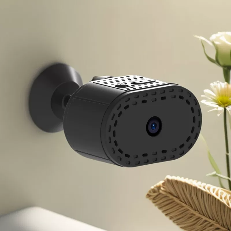 Black security camera mounted on a wall with a light background
