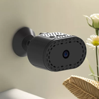 Black security camera mounted on a wall with a light background