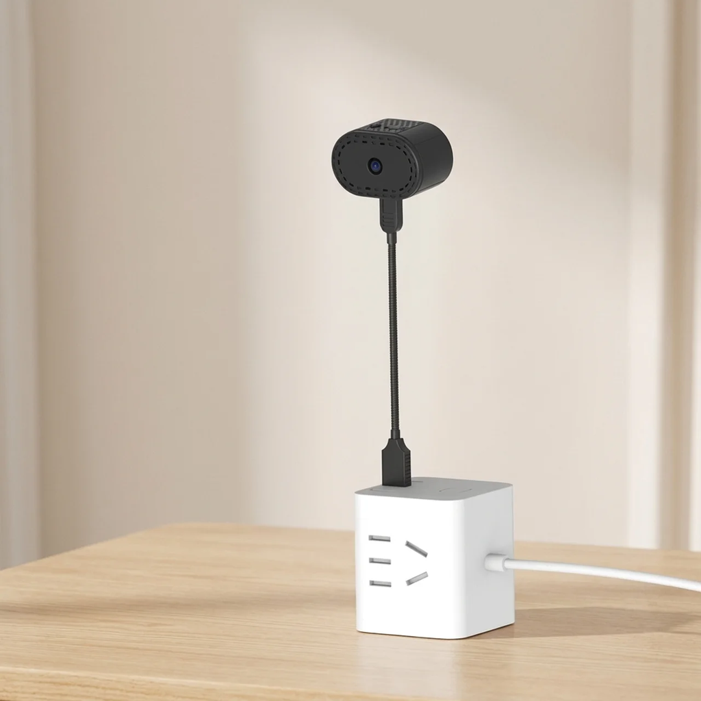 Small camera attached to a white cube on a wooden surface with a beige background