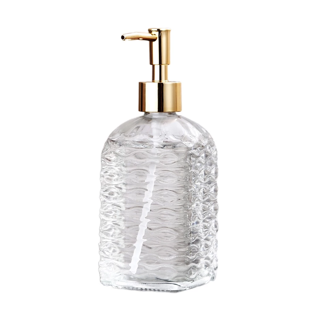 Clear glass soap dispenser with gold pump on a white background