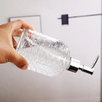 Clear soap dispenser with a hand holding it against a light background