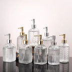 Set of glass soap dispensers with various designs on a reflective surface.