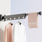 Wall-mounted clothes rack with hanging clothes and a towel on a light background