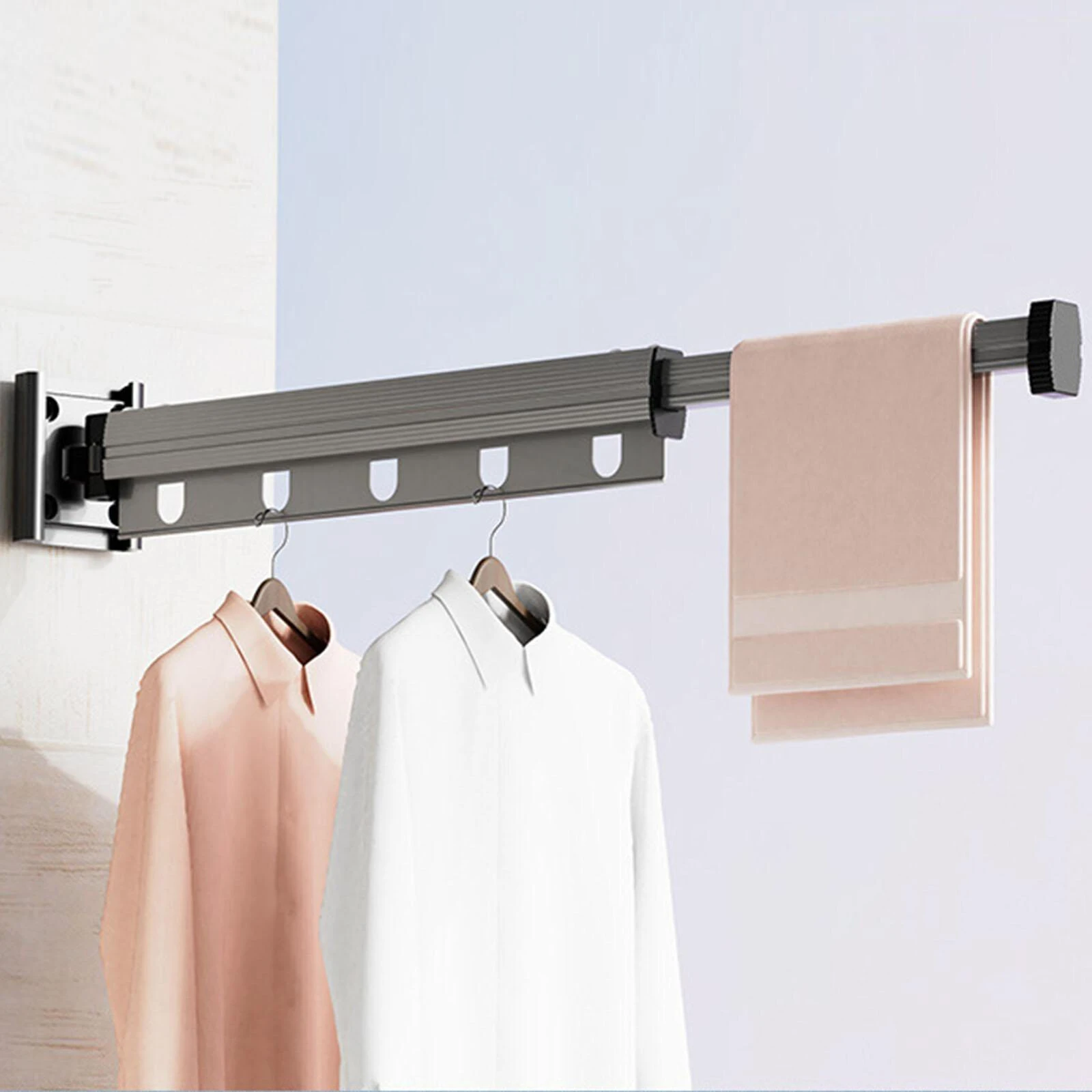 Wall-mounted clothes rack with hanging clothes and a towel on a light background