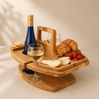 Wooden wine tray with a bottle, two glasses, croissant, and fruits on a beige background
