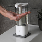 Hand using a white and clear soap dispenser on a bathroom counter.