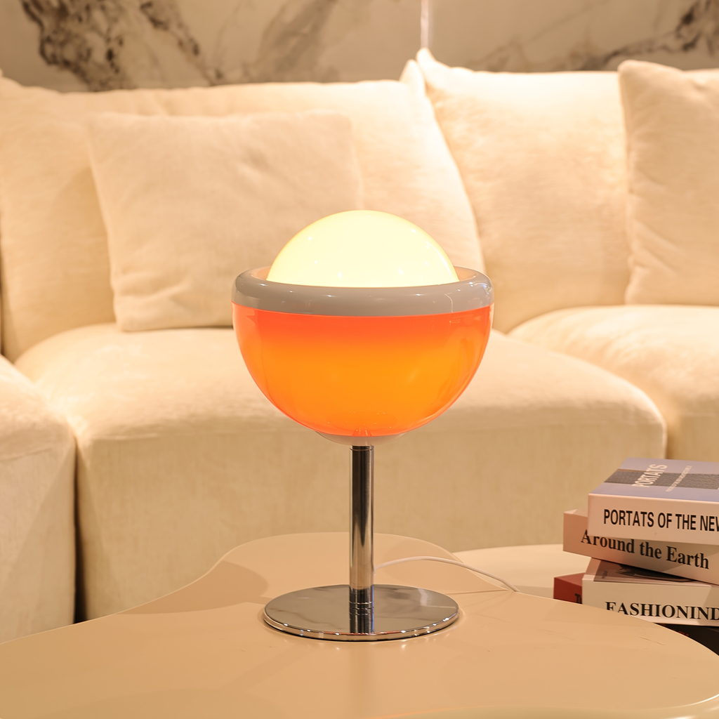 Table lamp with orange and white design on a table next to a beige sofa.