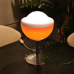 Decorative lamp with a white top and orange bottom on a dark surface.