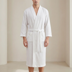 Person wearing a white textured bathrobe in a minimalistic setting