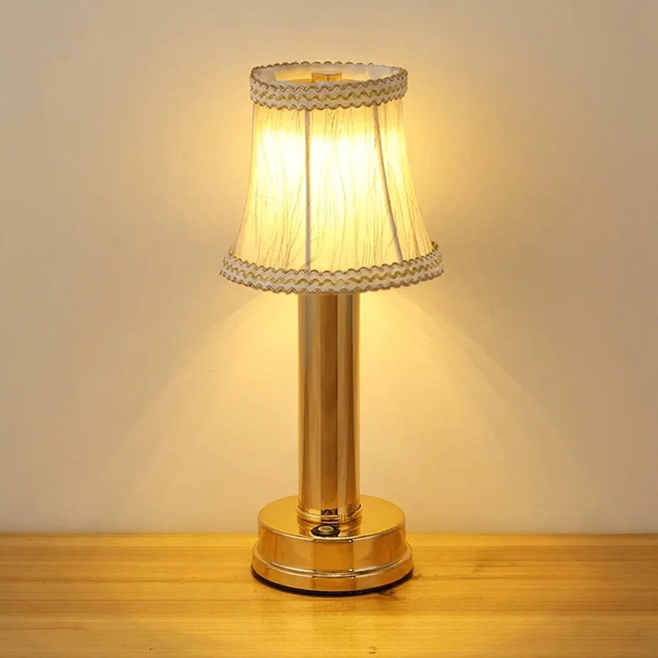 Decorative table lamp with a gold base and pleated white shade on a wooden surface.