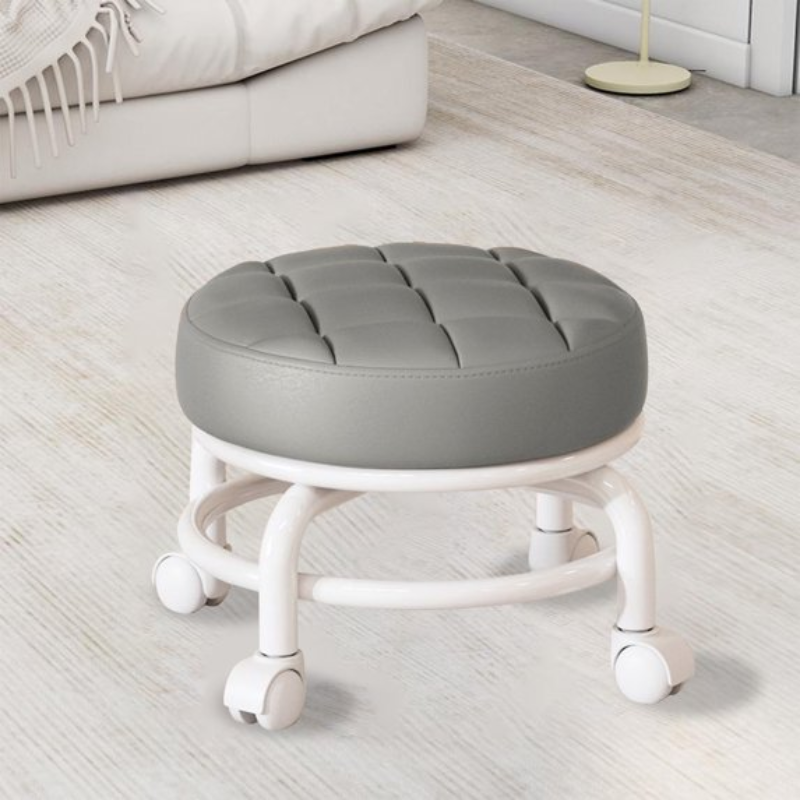 Gray cushioned stool with wheels on a light wooden floor.