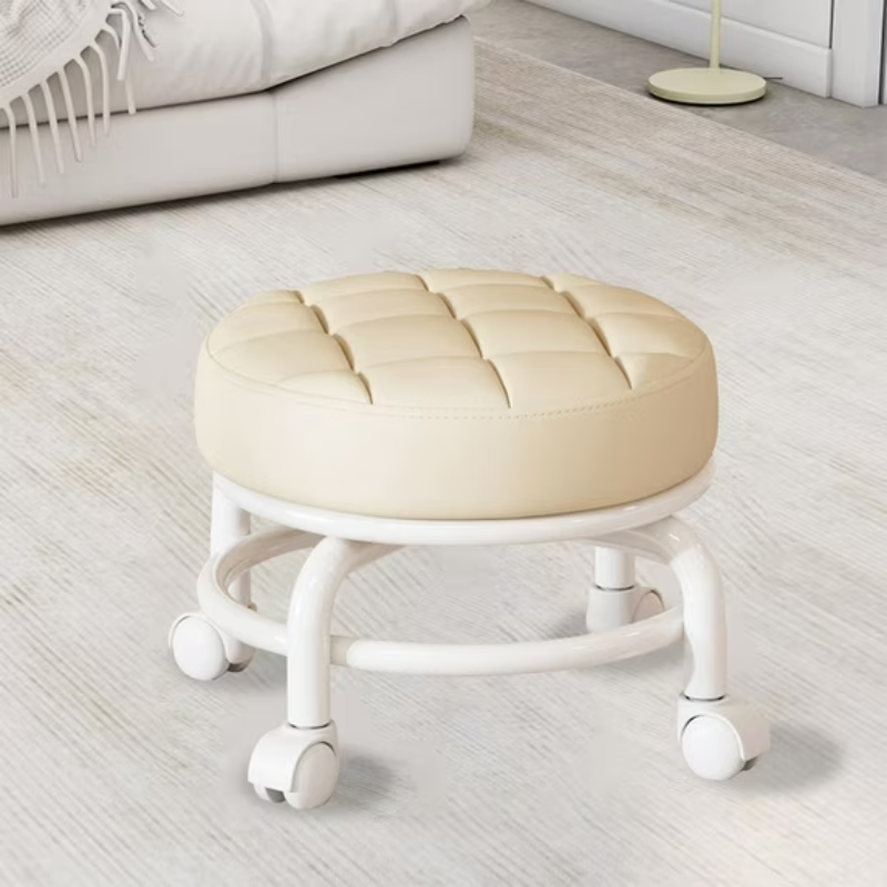Round cream-colored stool with white legs on a light wooden floor.