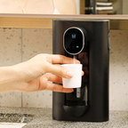 Person using a black water dispenser to fill a white cup with water.