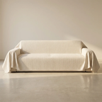 Beige sofa with a matching cover in a minimalistic room.