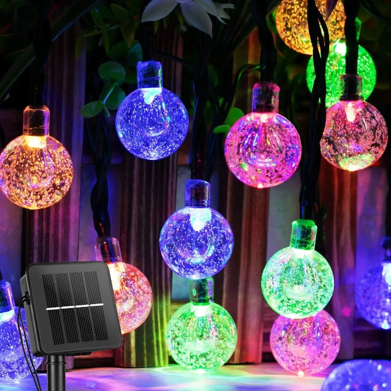 Colorful glass globe string lights with a solar panel on a dark background