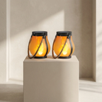 Two illuminated lanterns on a pedestal against a neutral wall