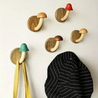 Wooden mushroom-shaped hooks on a white wall with colorful tops.