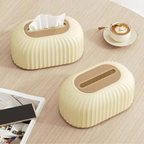 Two beige tissue boxes on a wooden surface with a cup of coffee and phone.