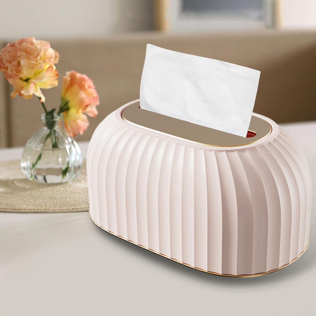 Decorative tissue box with pleated design on a table with flowers in the background