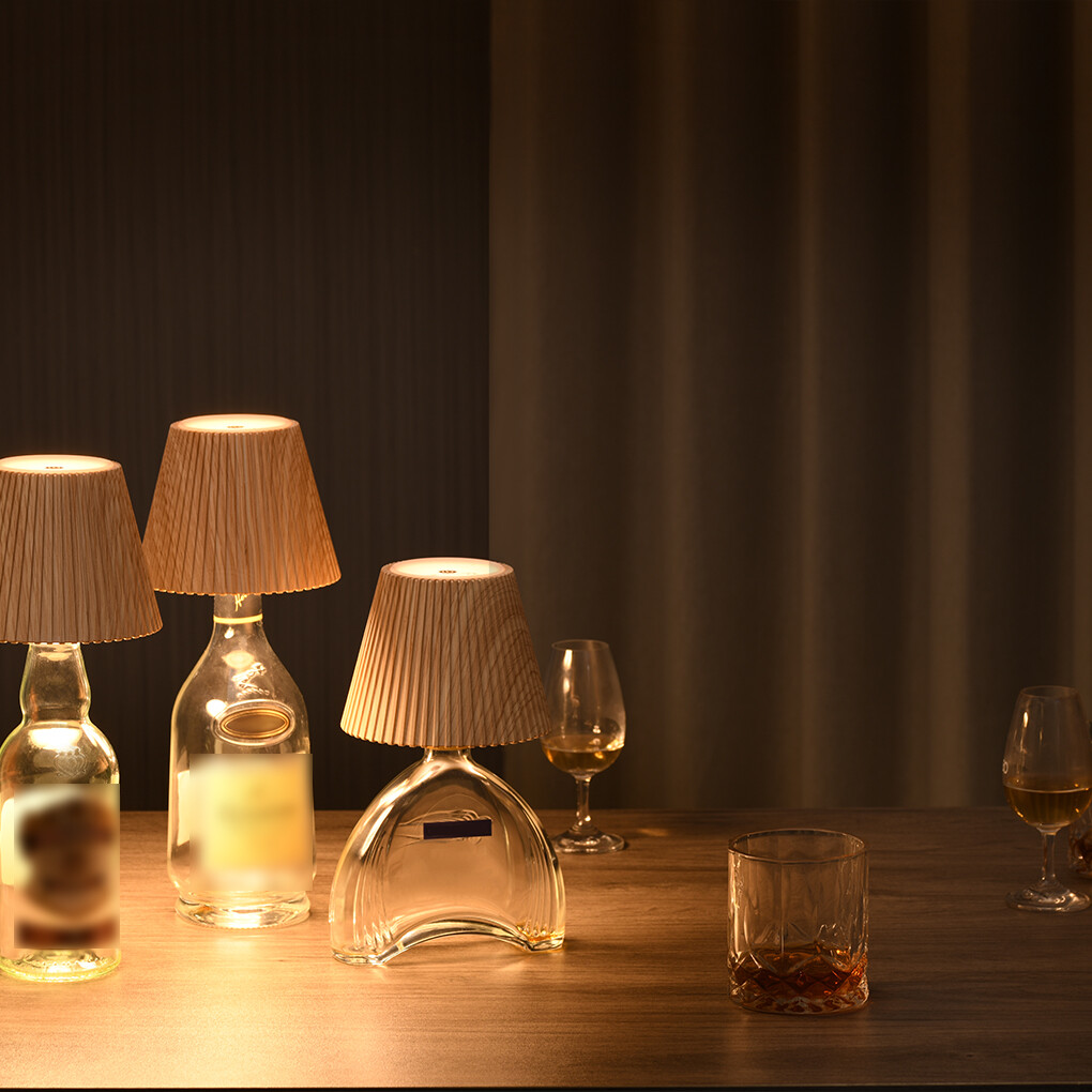 Three lampshades on bottles with glasses of liquid on a wooden surface.