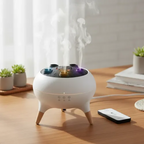 White essential oil diffuser with colorful stones on a wooden table, emitting steam.