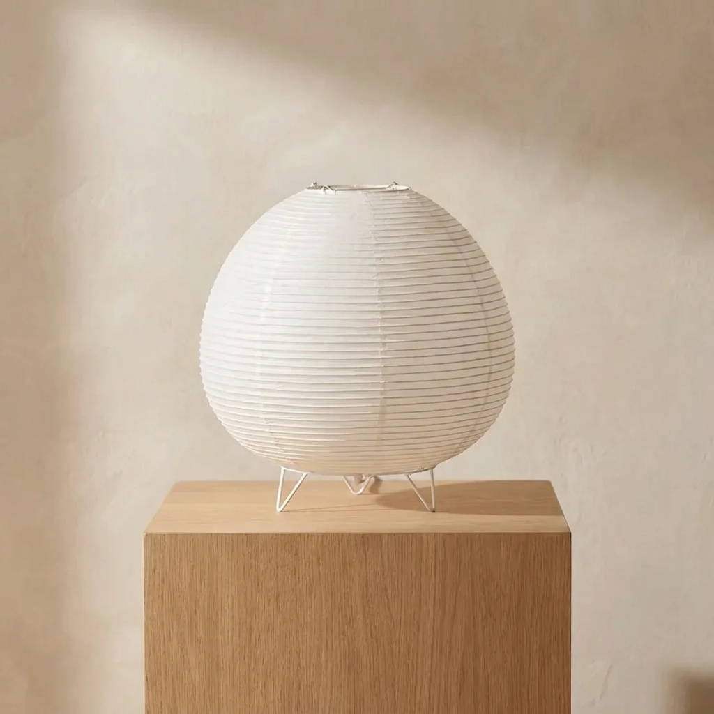 Spherical lamp on a wooden pedestal against a beige wall