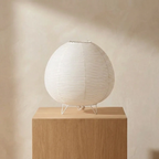 Spherical lamp on a wooden pedestal against a beige wall