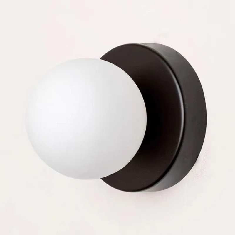 Modern wall-mounted light fixture with a matte black circular backplate and a frosted white spherical glass shade, shown against a plain off-white background.