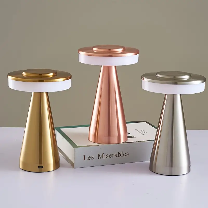Three decorative stools with gold, rose gold, and silver finishes on a neutral background.